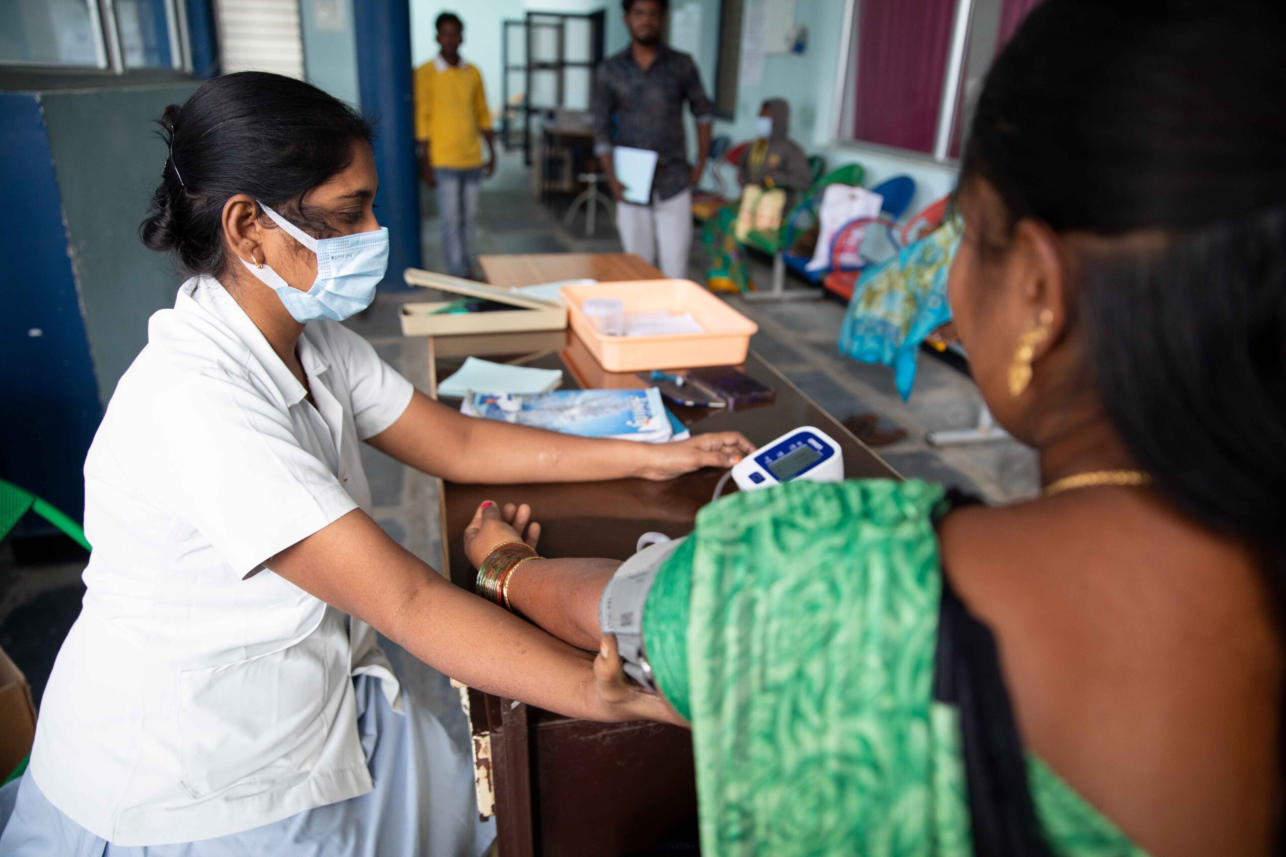 A woman wearing a face mask is checking her blood pressure in the Department of Internal & Family Medicine at Bathalapalli.